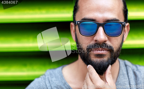 Image of close up of man in sunglasses touching beard