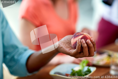 Image of male hand holding peach