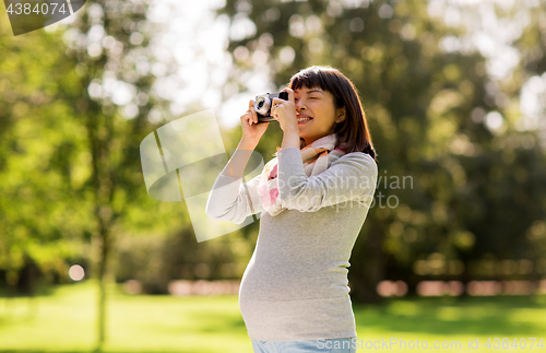 Image of happy pregnant asian woman with camera at park