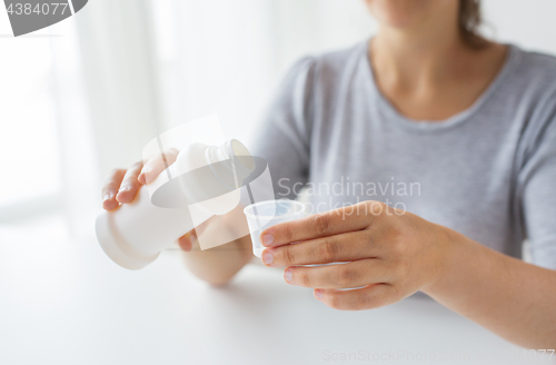 Image of woman pouring syrup from bottle to medicine cup