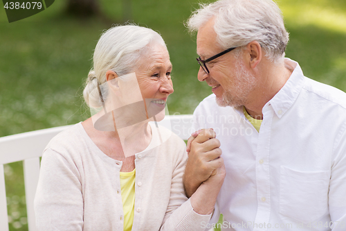 Image of happy senior couple sitting on bench at park