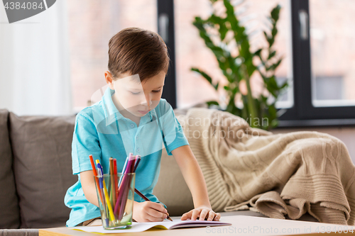 Image of boy with notebook and pencils drawing at home