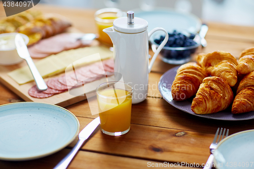 Image of coffeepot and glass of juice on table at breakfast