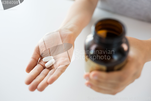 Image of close up of hands holding medicine pills and jar