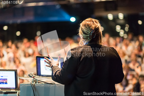 Image of Female public speaker giving talk at Business Event.