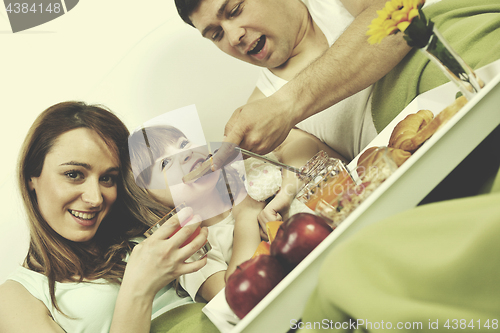 Image of happy young family eat breakfast in bed