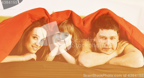 Image of happy family relaxing in bed