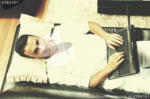 Image of Portrait of a relaxed young guy using laptop at home