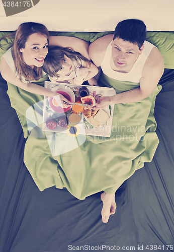 Image of happy young family eat breakfast in bed