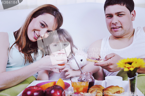 Image of happy young family eat breakfast in bed