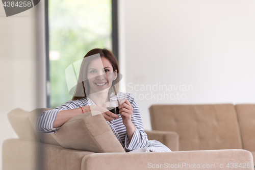 Image of young woman in a bathrobe enjoying morning coffee