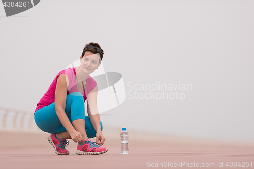 Image of Young woman tying shoelaces on sneakers