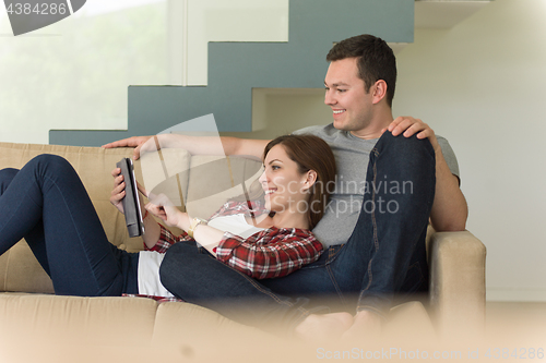 Image of couple relaxing at  home with tablet computers