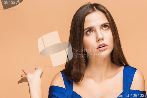 Image of Beautiful young brunette woman posing in a blue dress. Studio