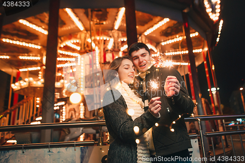 Image of Young couple kissing and hugging outdoor in night street at christmas time