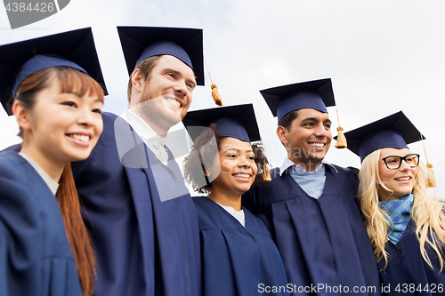 Image of happy students or bachelors in mortar boards