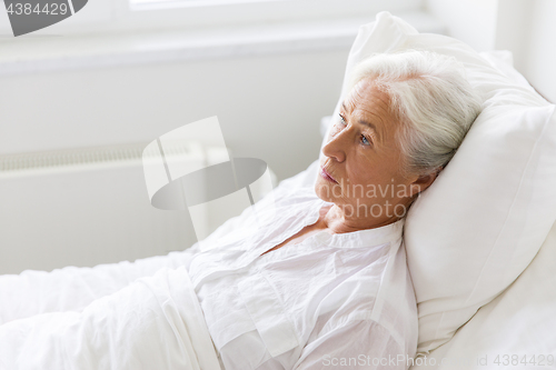 Image of sad senior woman lying on bed at hospital ward