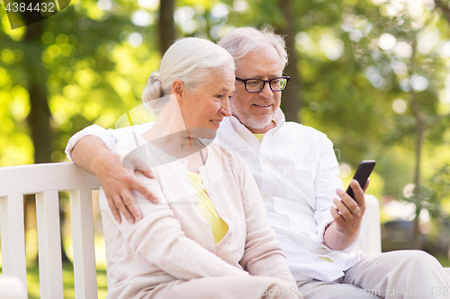 Image of happy senior couple with smartphone at park