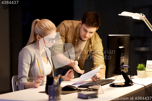 Image of business team with papers working late at office