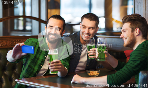 Image of friends taking selfie with green beer at pub