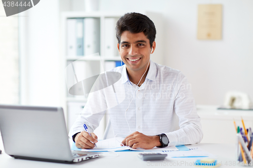 Image of businessman in earphones working at office