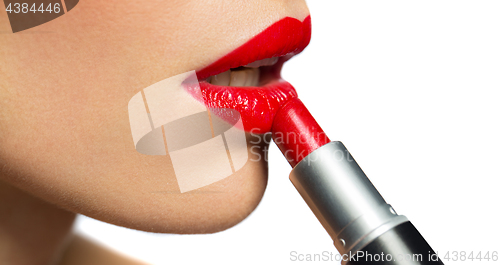 Image of close up of woman applying red lipstick to lips