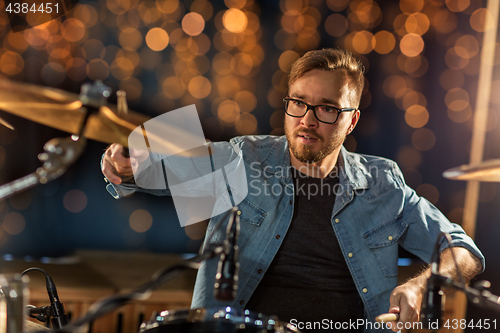 Image of musician playing drum kit at concert over lights