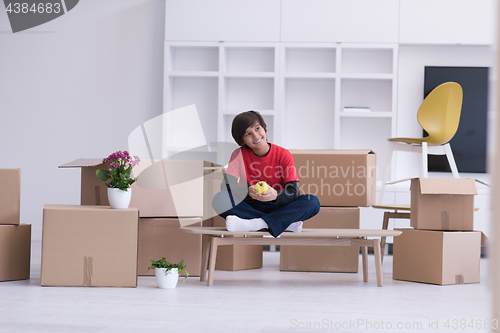 Image of boy sitting on the table with cardboard boxes around him