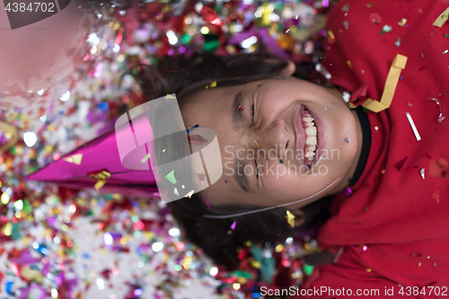 Image of kid blowing confetti while lying on the floor