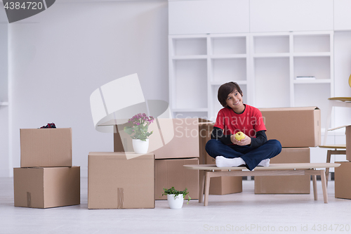 Image of boy sitting on the table with cardboard boxes around him