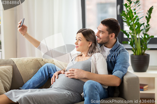 Image of man and pregnant woman taking selfie at home