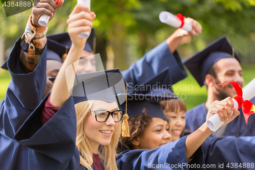 Image of happy students in mortar boards with diplomas