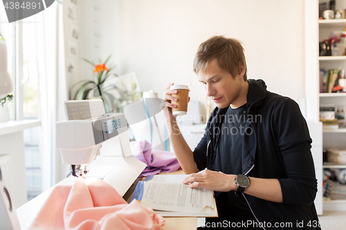 Image of fashion designer with coffee and book at studio