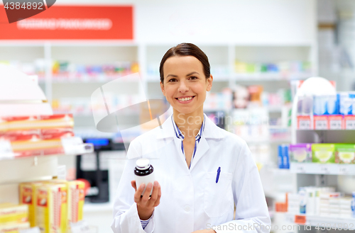 Image of happy female apothecary with drug at pharmacy