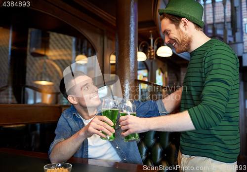 Image of male friends drinking green beer at bar or pub