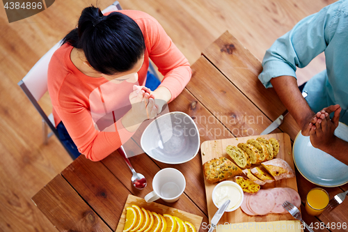 Image of woman sitting at table and praying before meal