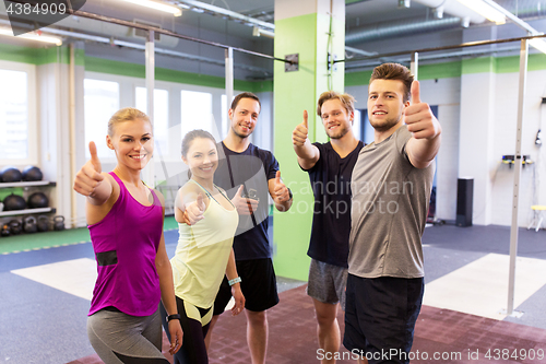 Image of group of happy friends in gym showing thumbs up