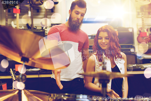 Image of couple of musicians with drum kit at music store