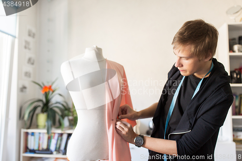 Image of fashion designer with dummy making dress at studio