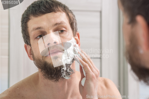 Image of A man is applying shaving foam to his face preparing to shave