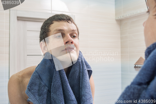 Image of A young man shaved and washed himself wiping himself dry with a towel