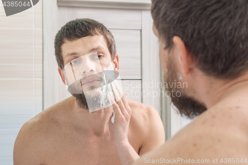 Image of A man is applying shaving foam to his face preparing to shave