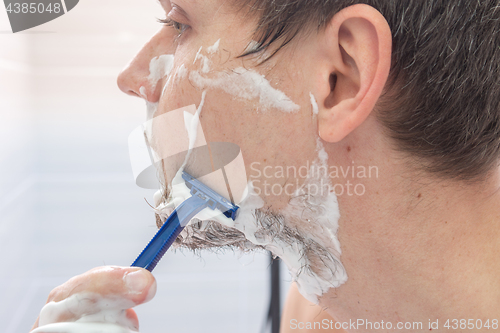 Image of The guy shaves his left cheek, close-up