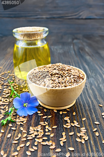 Image of Flaxen brown seed in bowl with flower and oil on board