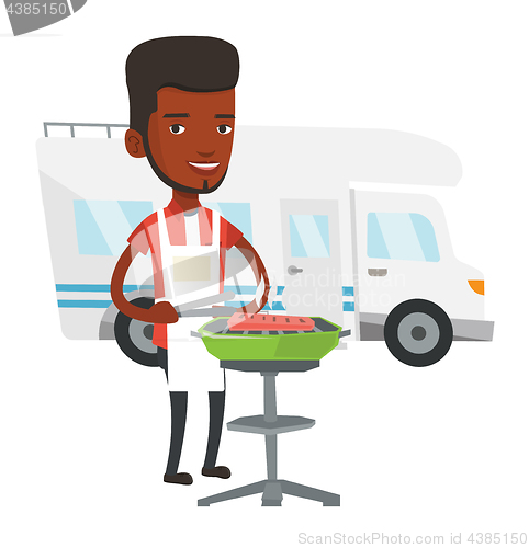 Image of Man having barbecue in front of camper van.