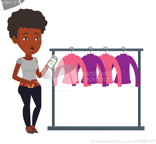 Image of Woman shocked by price tag in clothing store.