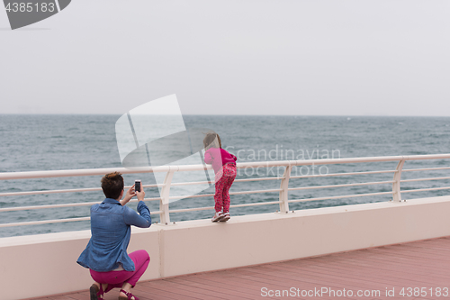 Image of mother and cute little girl on the promenade by the sea