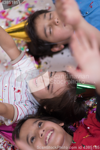 Image of kids  blowing confetti while lying on the floor