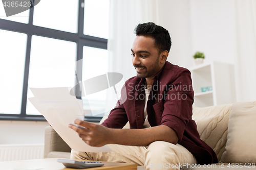 Image of man with papers and calculator at home