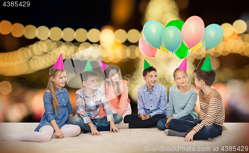 Image of happy smiling children in party hats at birthday